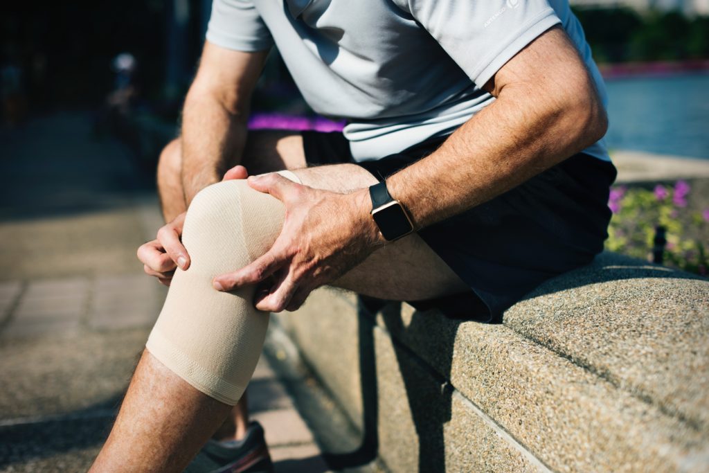 Lesões no Esporte - Homem sentado com Lesão no joelho